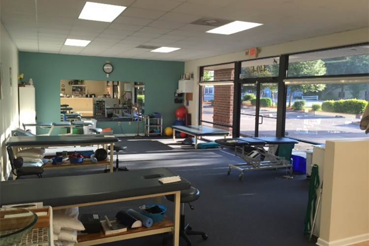 Inside Grace Physical Therapy & Sports Rehab showing adjustment tables, equipment, front desk and the storefront